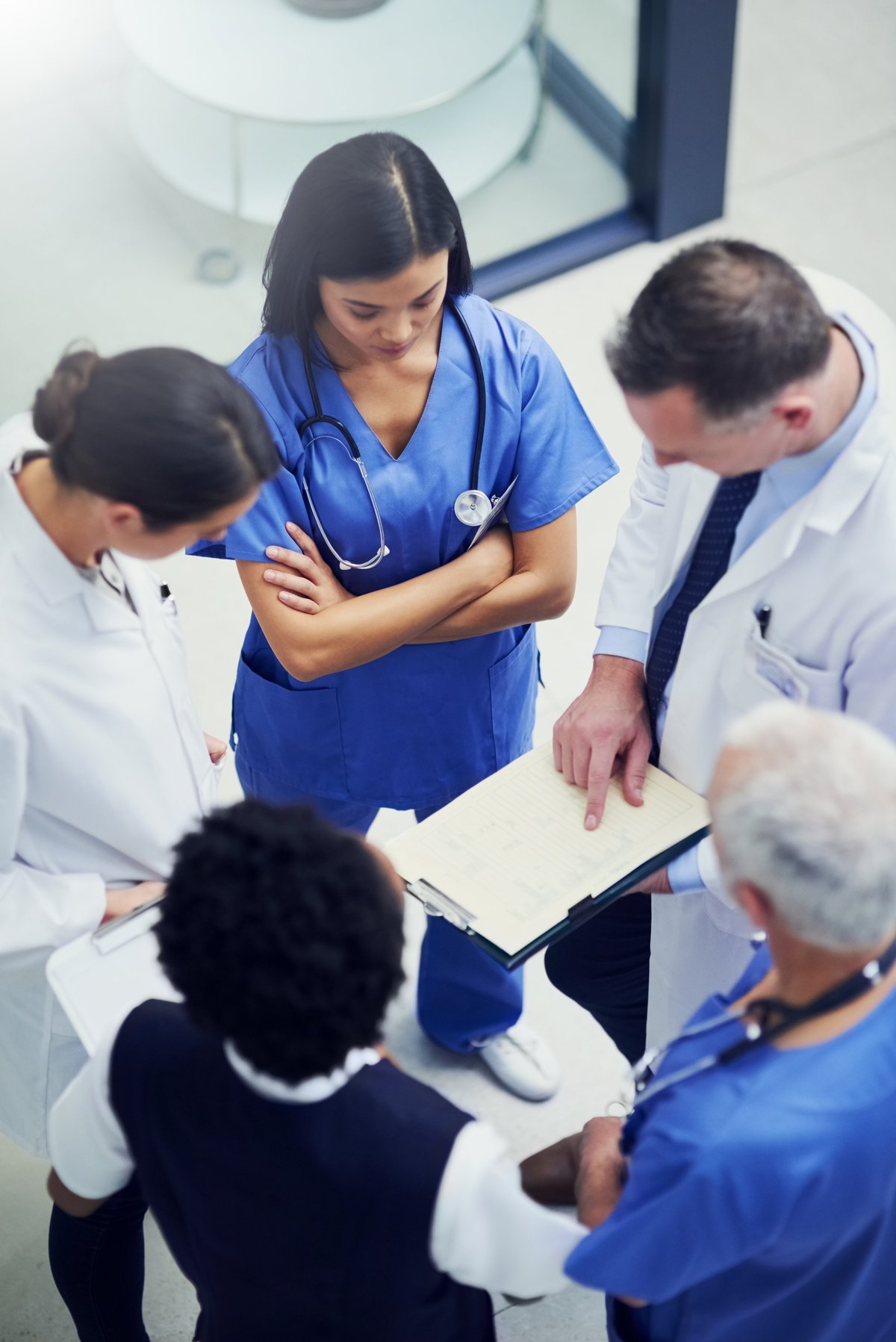 Shot of a group of doctors talking together over a medical chart while standing in a hospital