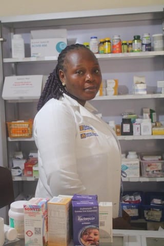 Healthcare professional in white coat posing in front of shelves stocked with medical supplies and skincare products