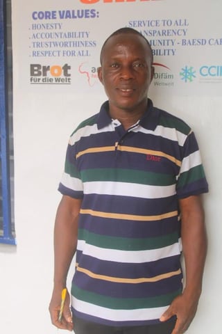 Man in striped polo shirt smiling at camera in front of core values poster